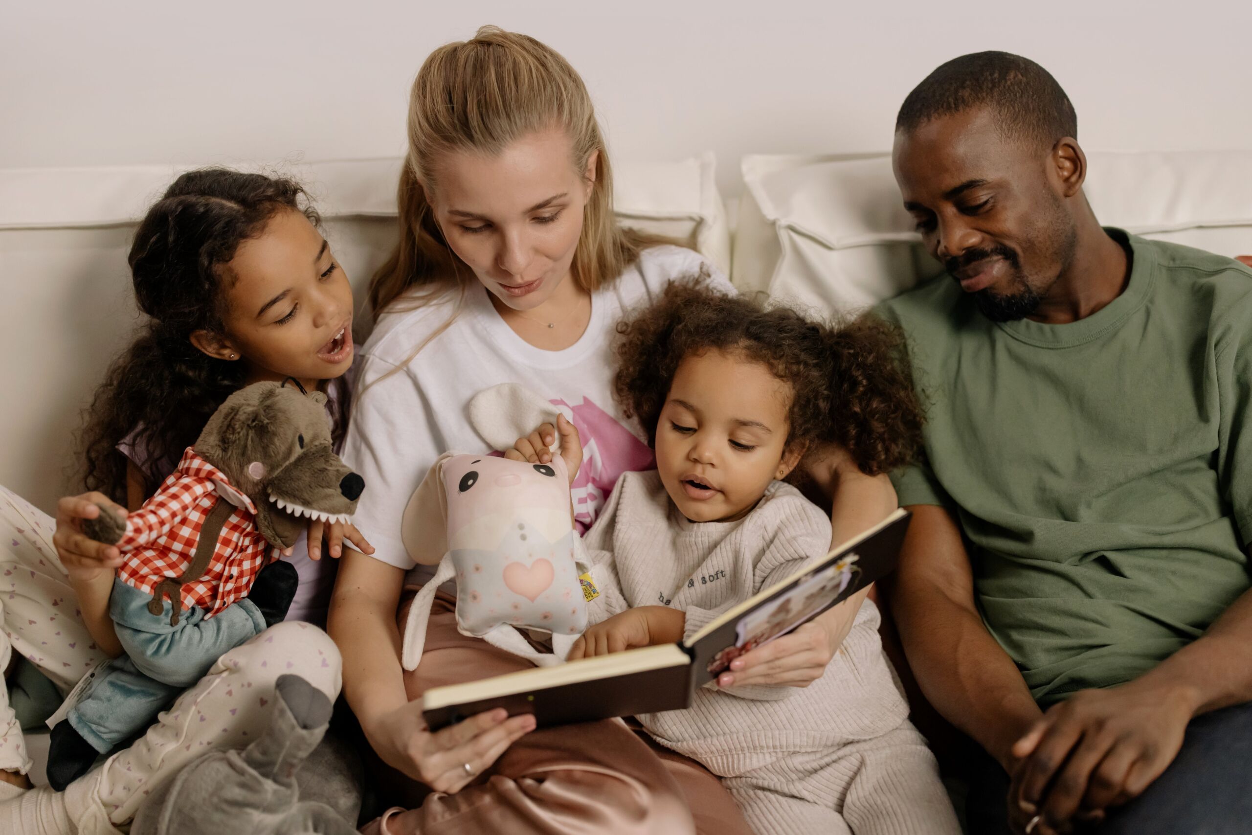 parents reading book to children in bed
