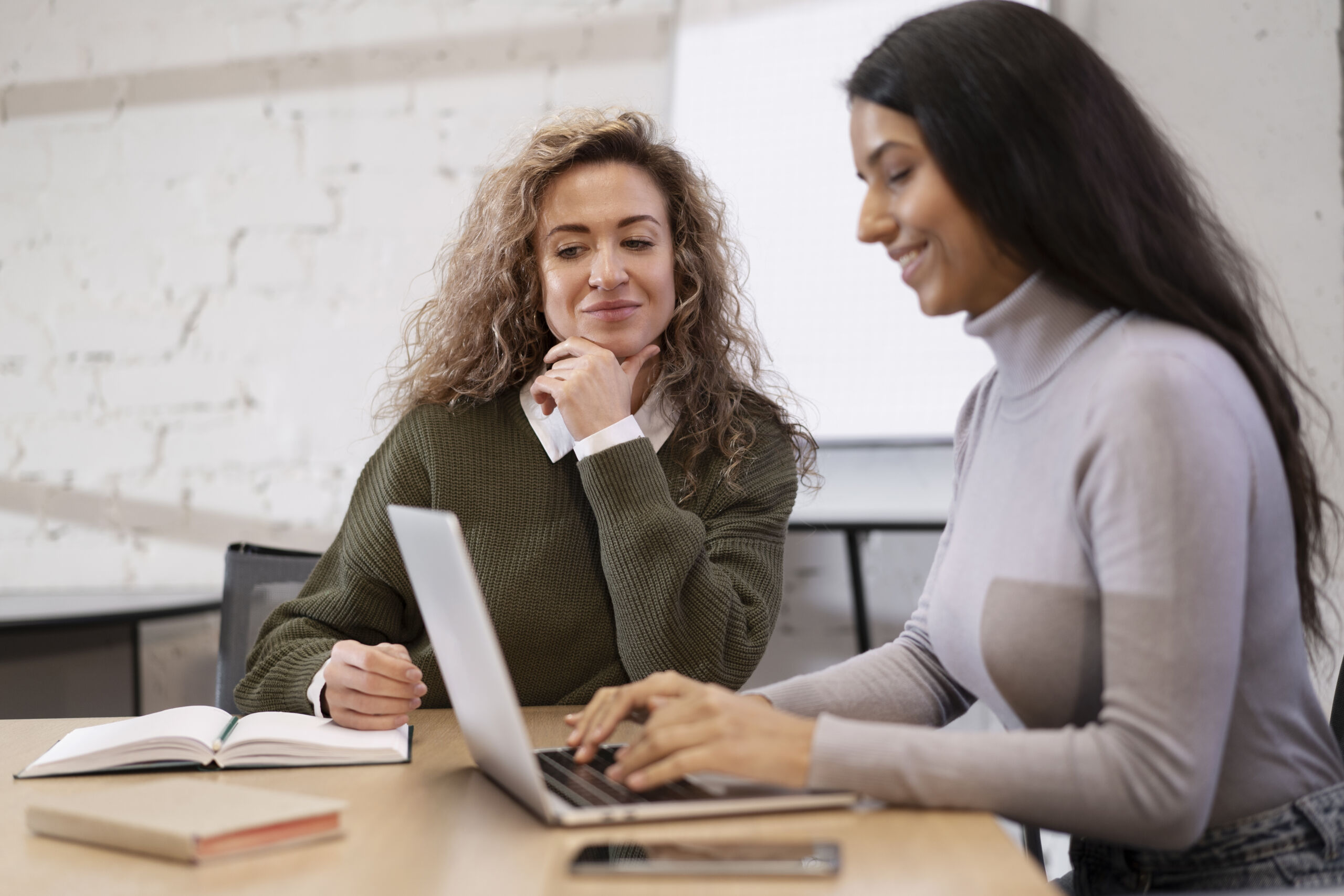 two people at a desk working on a computer