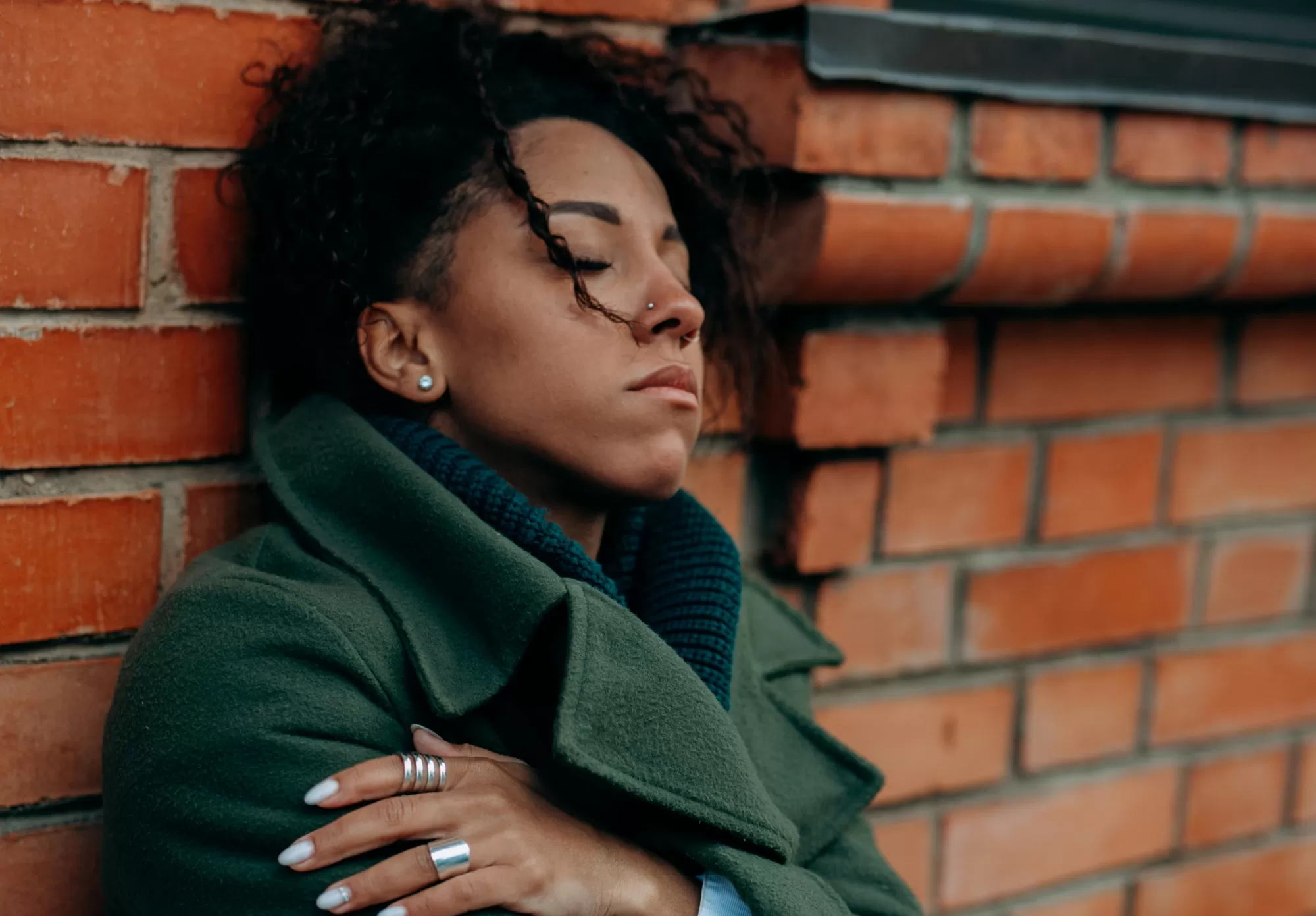 woman sitting against a red brick wall